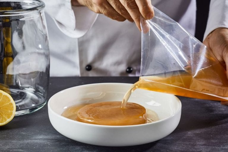 Man pouring starter tea on scoby to make homemade kombucha