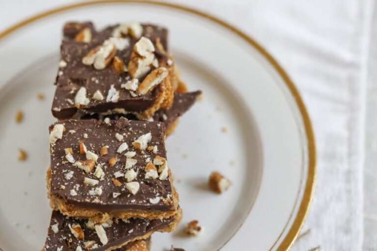 Chocolate Cracker Toffee Topped With Chopped Nuts on a White Plate