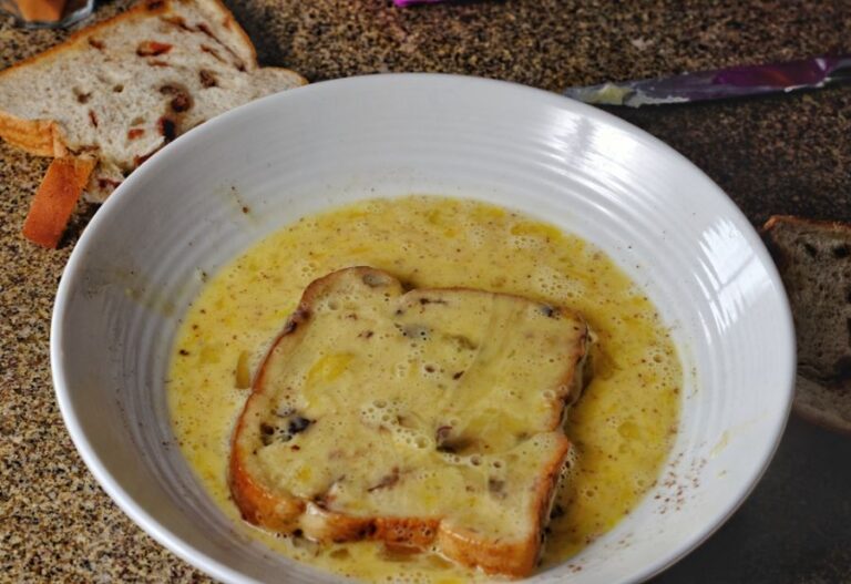 Piece of Raisin Bread Soaking in Egg and Milk Mixture for French Toast