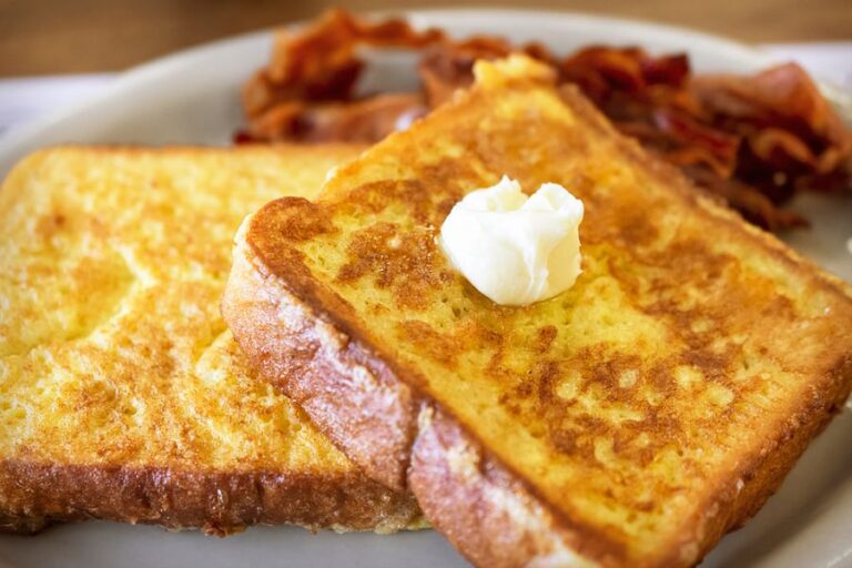 Two Pieces of French Toast With Bacon in the Background