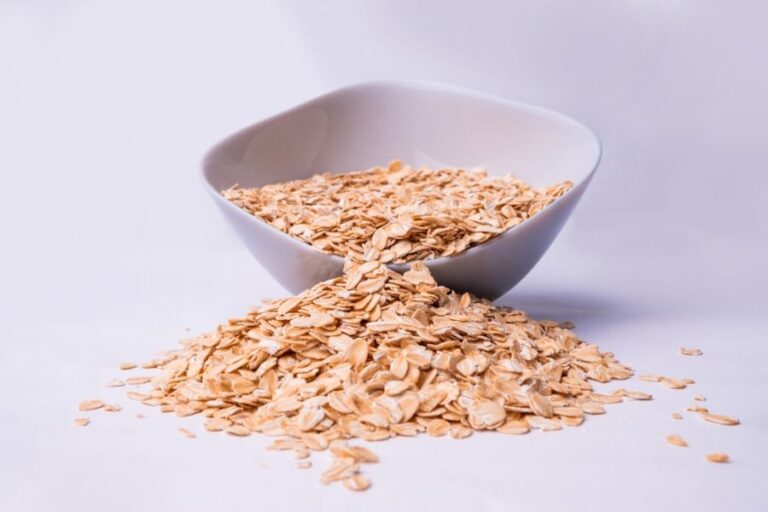 Bowl of Oats Spilling Out on to a White Background