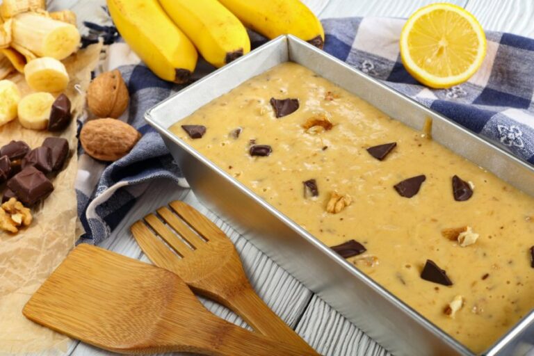 Unbaked Banana Bread in a Loaf Pan Surrounded by Various Add-Ins