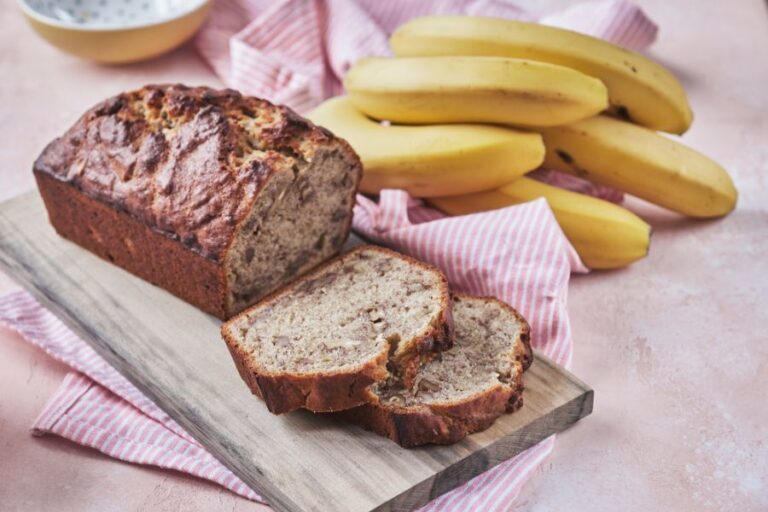 Sliced Banana Walnut Bread With Bunch of Bananas in the Background