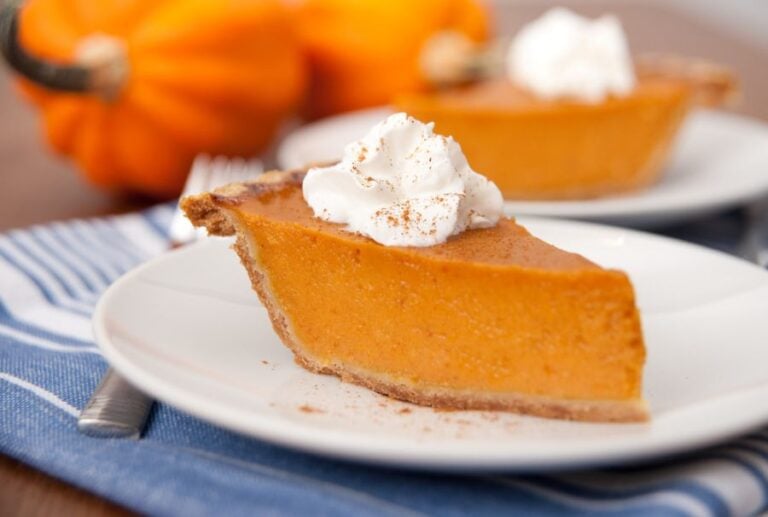 Slice of Pumpkin Pie With Whipped Cream on Top on a White Plate