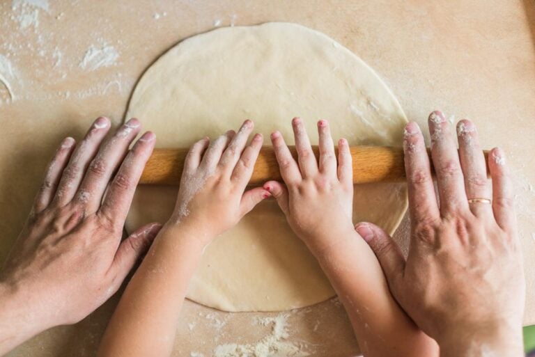 Adult and child hands together on a rolling pin
