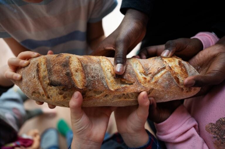 Multiple people sharing a loaf of bread