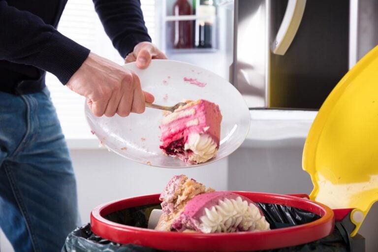 Scraping cake off of a plate into the garbage